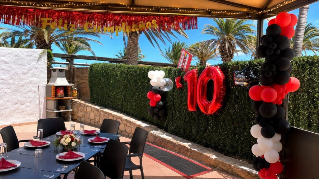Celebración de 10 años con temática años 80, globos rojos y número 10 en Bambino de Arinaga